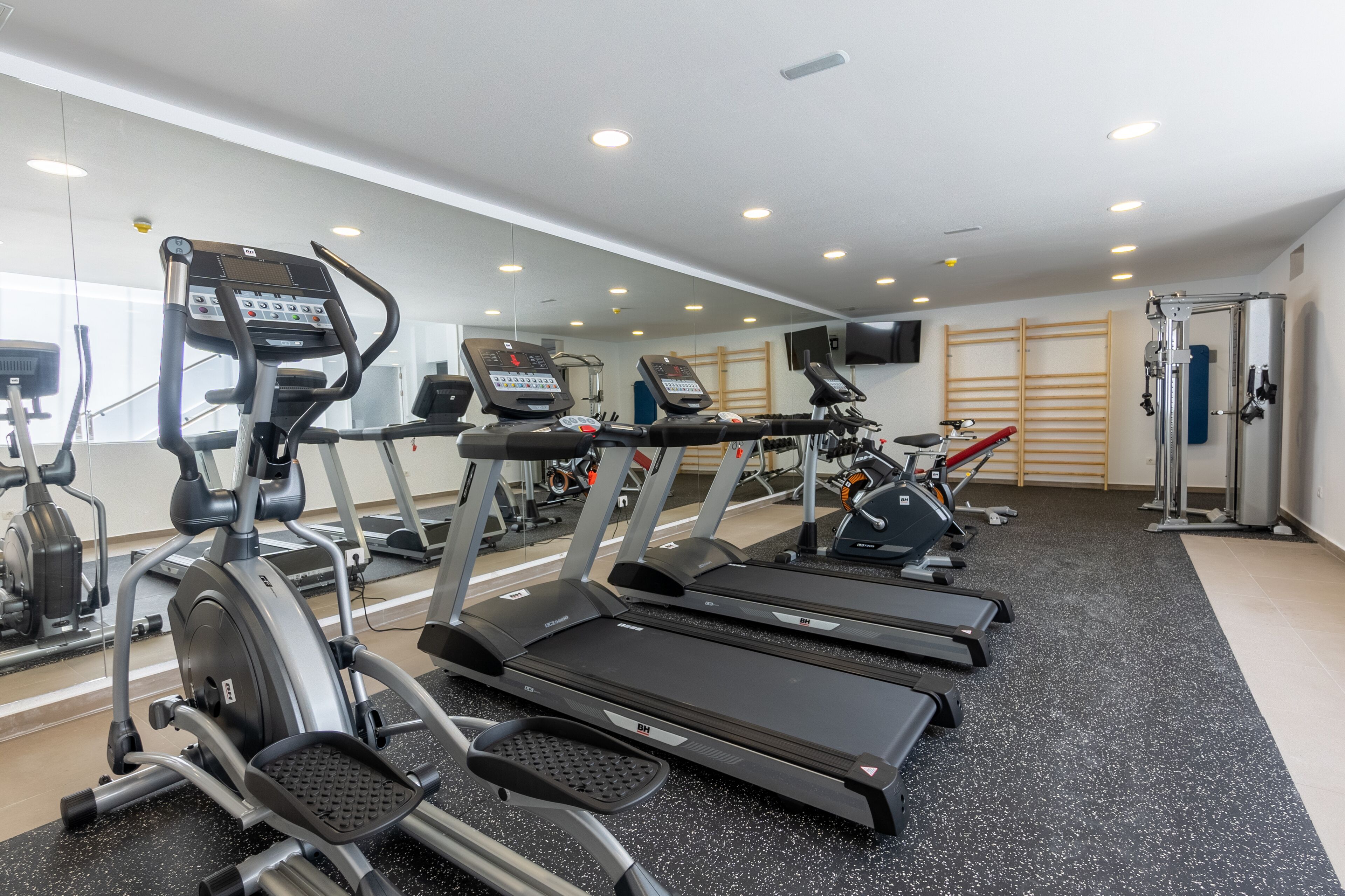 A gym with treadmills, elliptical machines, and weight equipment.