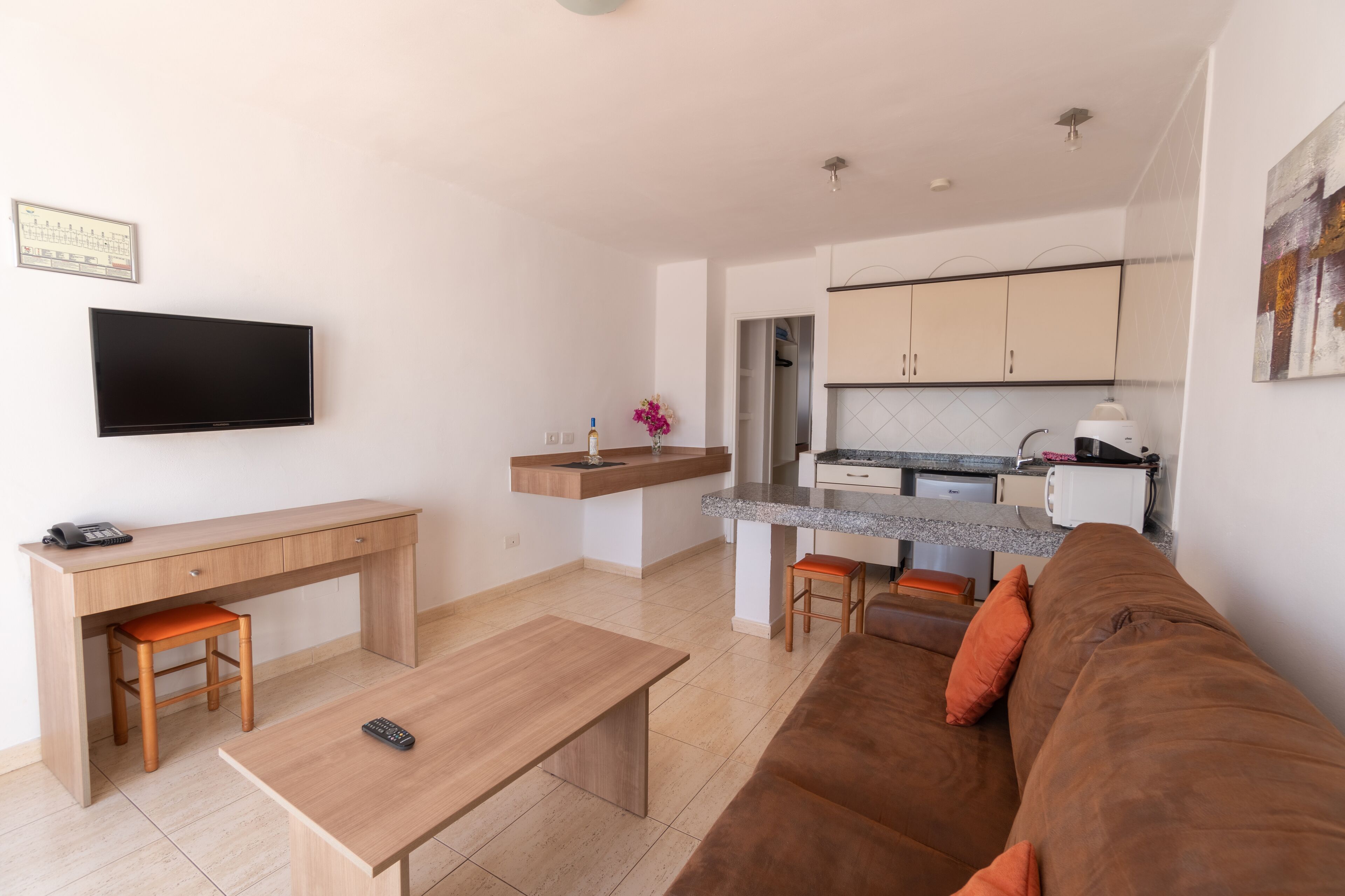 Una sala de estar moderna con un sofá marrón, una mesa de centro de madera y un televisor montado en la pared.
