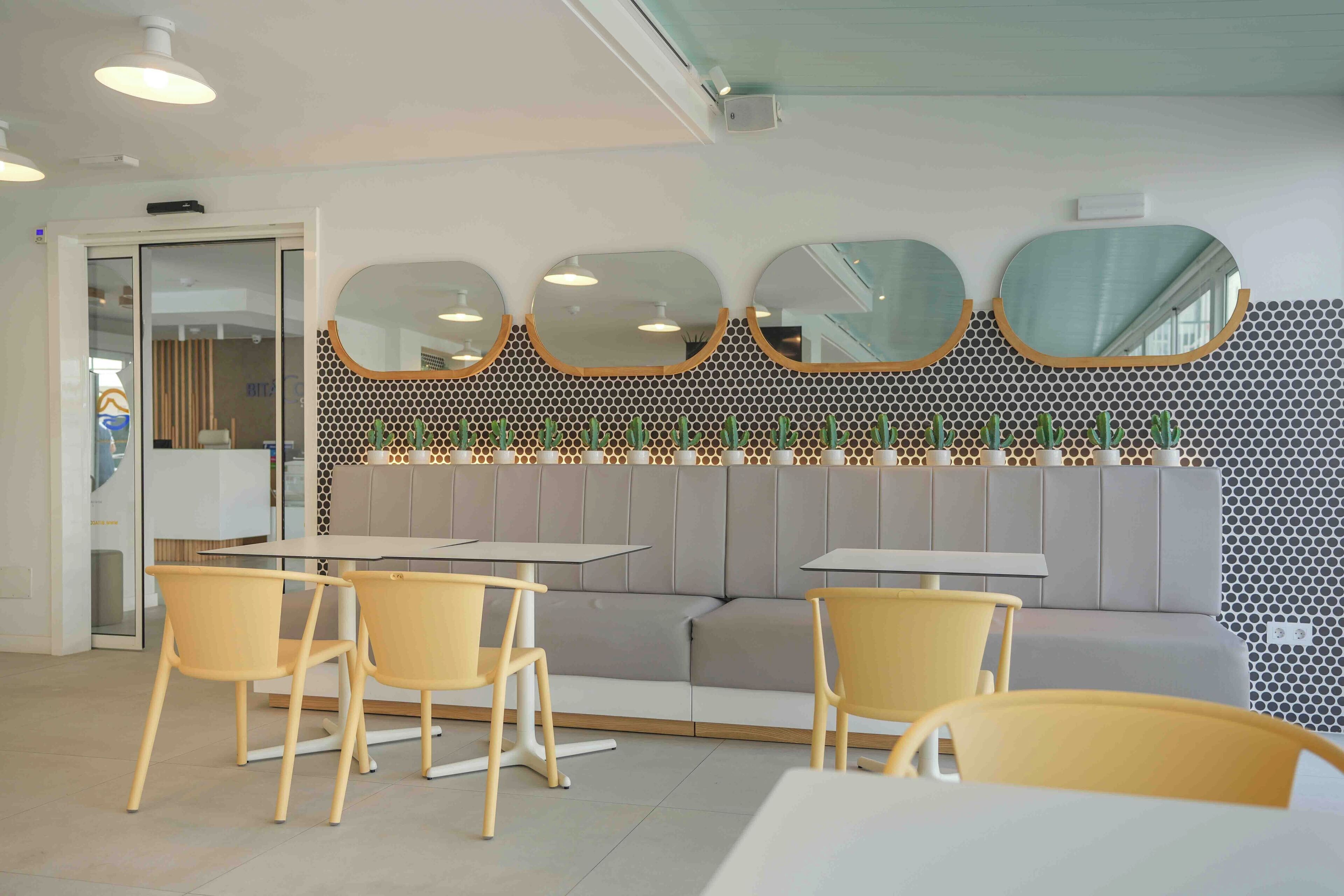 Un interno moderno con zona salotto, tavoli e una parete decorativa con specchi.