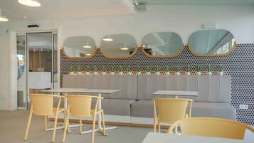 Un interno moderno con zona salotto, tavoli e una parete decorativa con specchi.