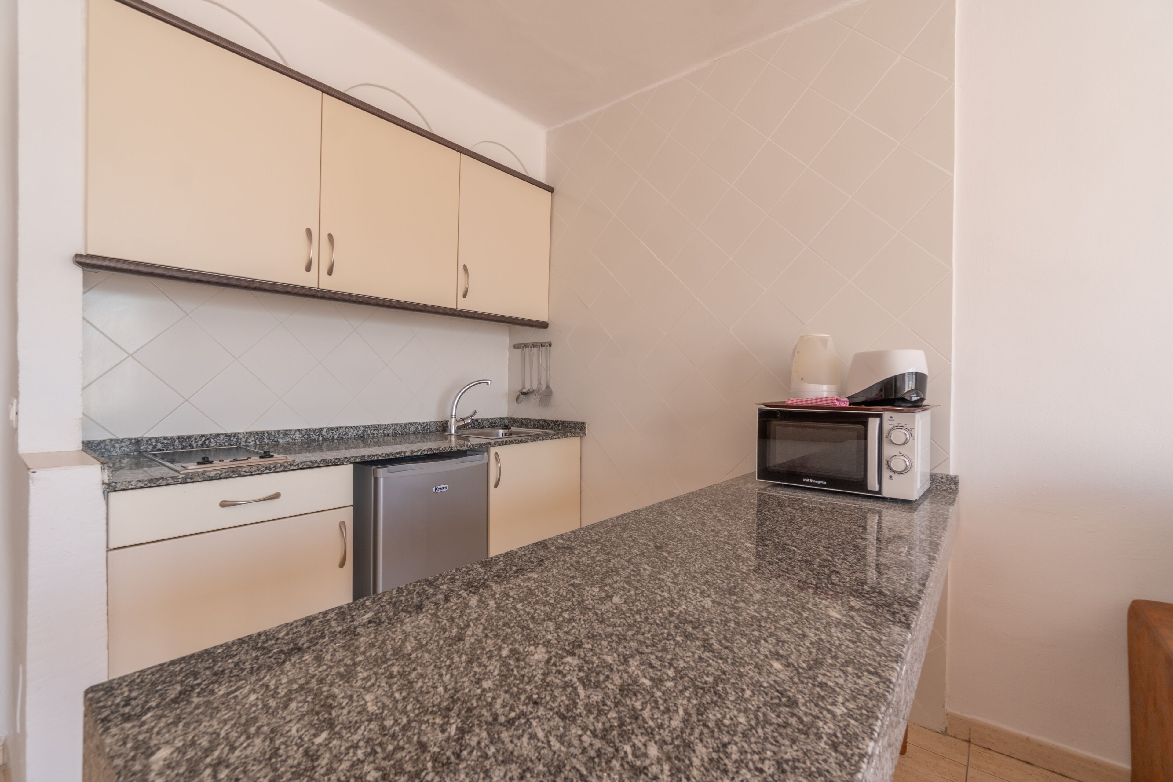 Una cocina con encimeras de granito, lavavajillas, microondas y un lavabo.