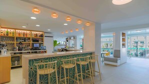 Un área de bar moderna con mostrador, taburetes y una variedad de botellas y vasos.