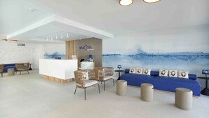 Vestíbulo moderno de hotel con mostrador de recepción, zona de estar y un gran mural azul.