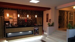 A hotel reception area with a wooden reception desk, a sign reading "RECEPTION", and a staircase leading to an upper level. - Hotel Gala (Cluj-Napoca)