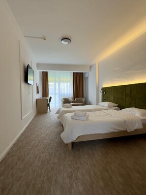 Une chambre d’hôtel avec un grand lit, un bureau, une chaise et un téléviseur.