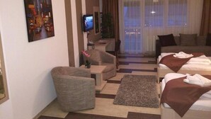 A hotel room with a sofa, a bed, a TV, and a painting on the wall. - Hotel Gala (Cluj-Napoca)