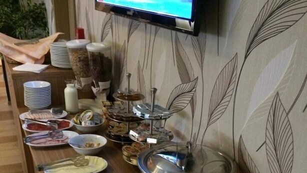A buffet setup with various dishes and a television mounted on the wall. - Hotel Gala (Cluj-Napoca)