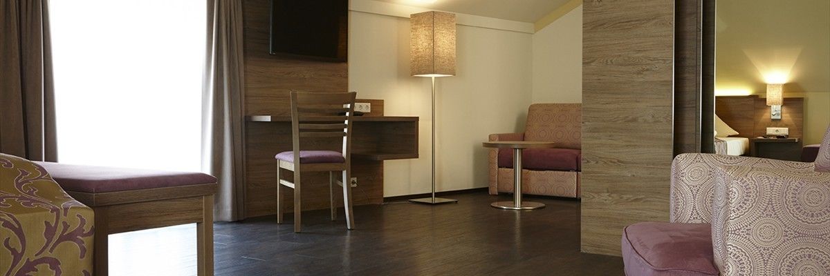 Una habitación de hotel con un escritorio de madera, una silla, una mesita pequeña y un sofá.