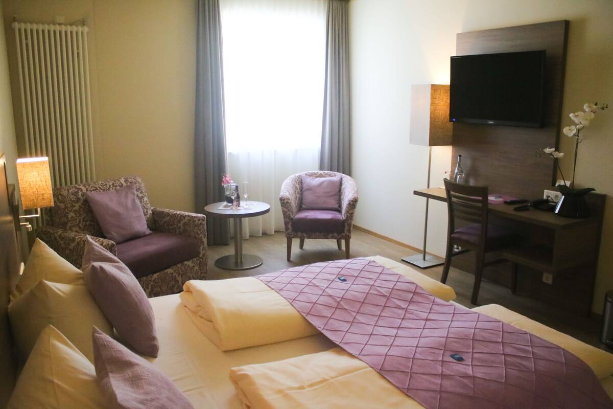 Une chambre d’hôtel comprenant un lit, deux fauteuils, un bureau, une télévision et une lampe.