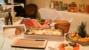 A buffet table with various food items, including meats, cheeses, and fruits.
