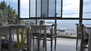 A modern dining area with white furniture and a view of the ocean. - The Hampton Guest House (East London)