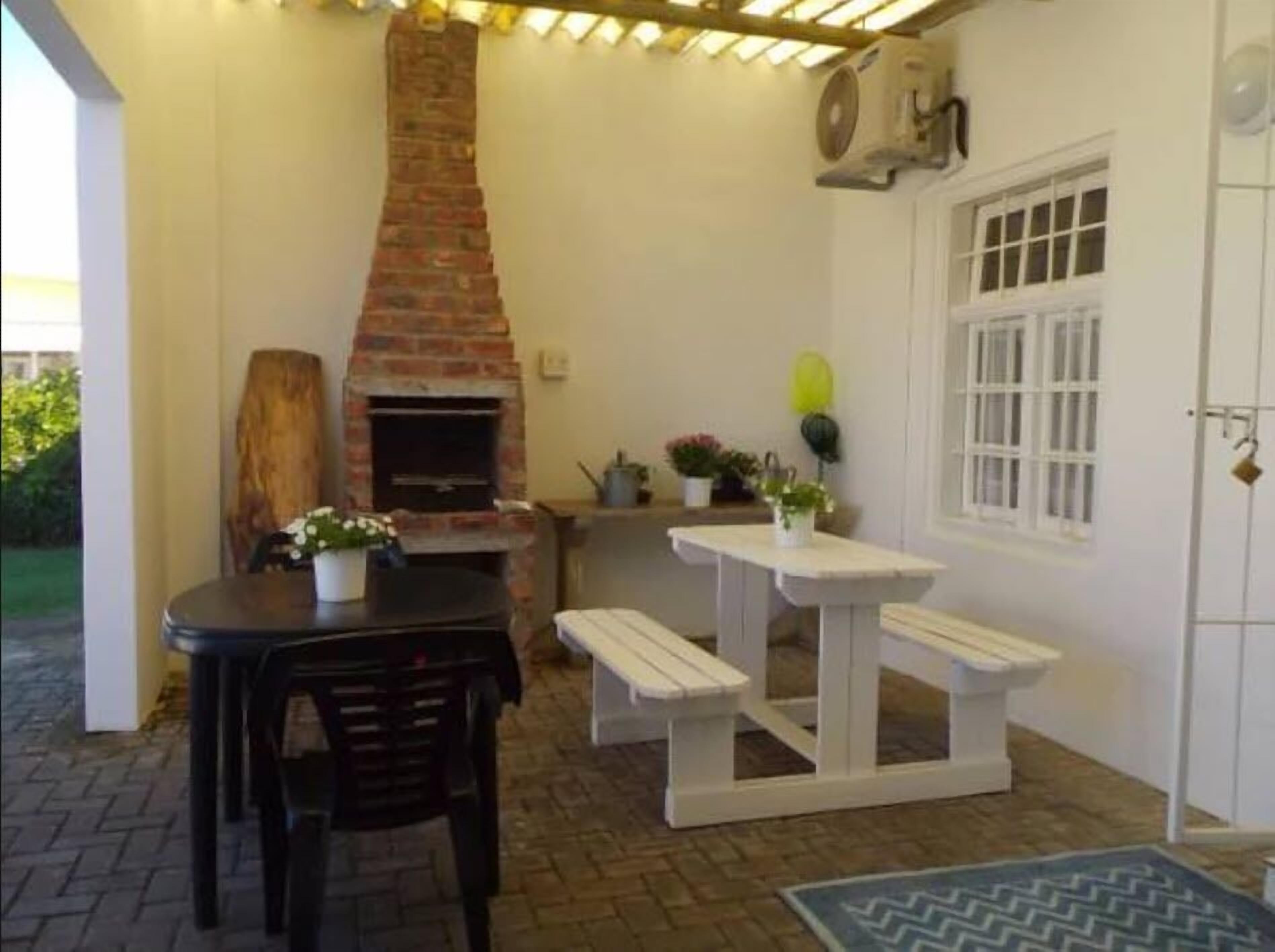 A patio area with a brick fireplace, a table with chairs, and a white door with windows.