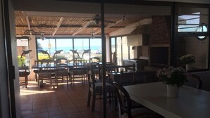 Un comedor interior con vista a la playa, una pared de ladrillo y una parrilla.