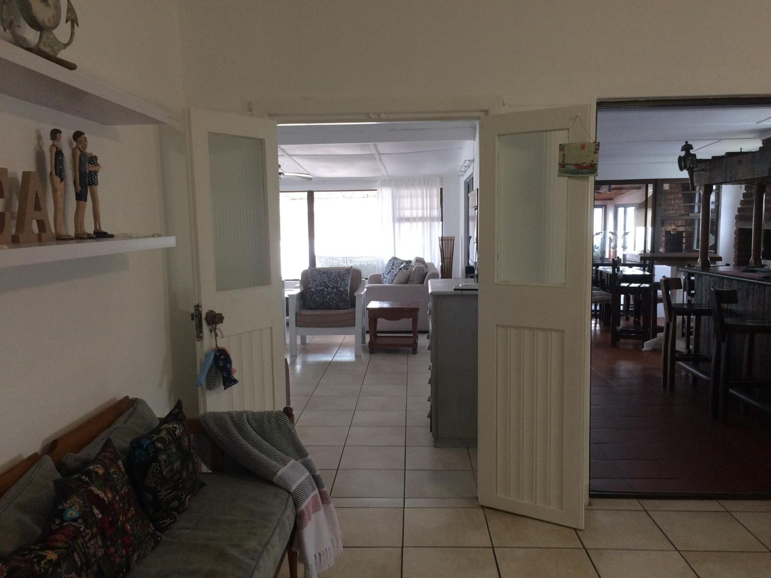 Amplia sala de estar con un sofá, una mesa de comedor y una cocina visible a través de un puerta abierta.