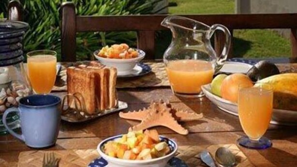 Una mesa de desayuno con vistas al océano y coches aparcados.