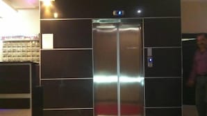 Un ascensor en el vestíbulo de un hotel con alfombra roja y un cartel a la izquierda.