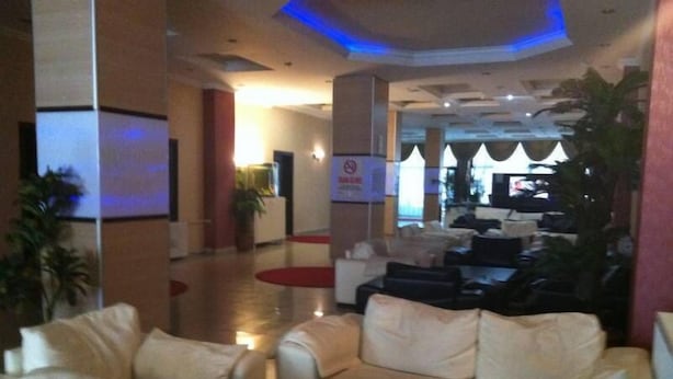Un vestíbulo con mostrador de recepción, zona de estar con sofás y una pantalla de televisión.