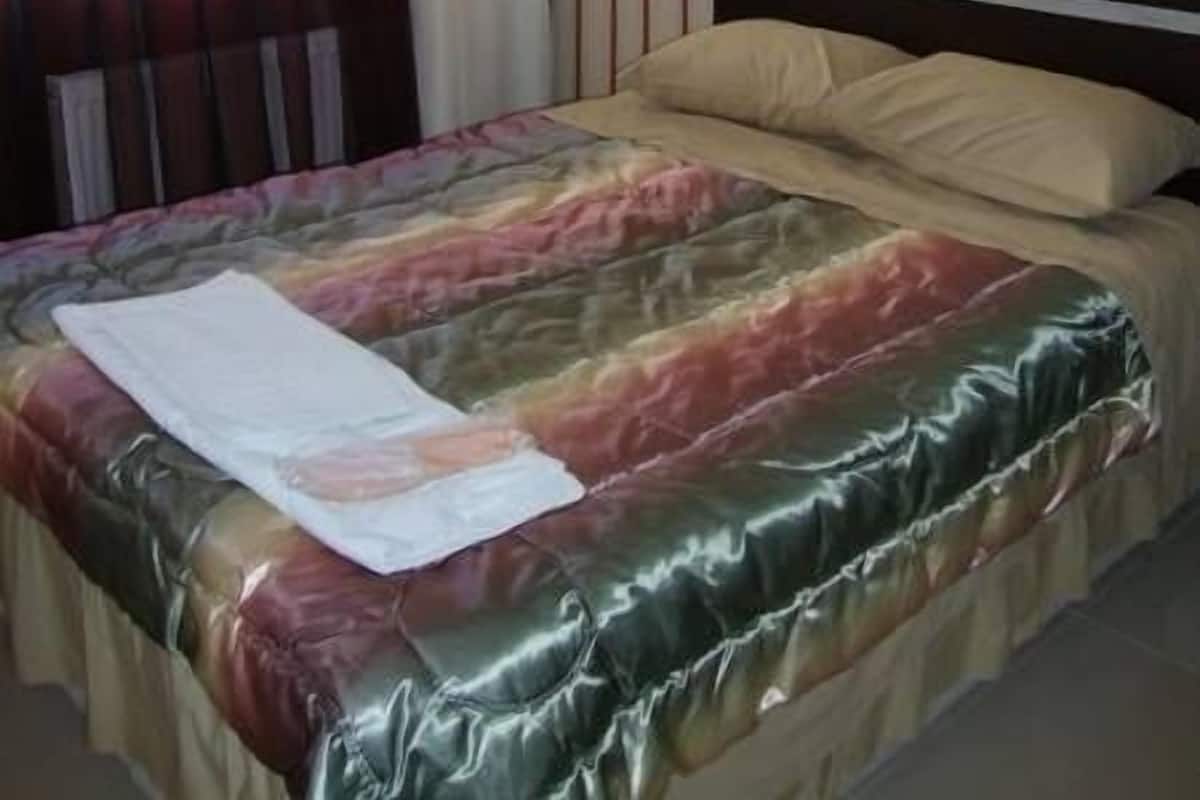 Ein Bett mit farbenfroher Bettdecke, einem Kissen und einem weißen Handtuch darauf.