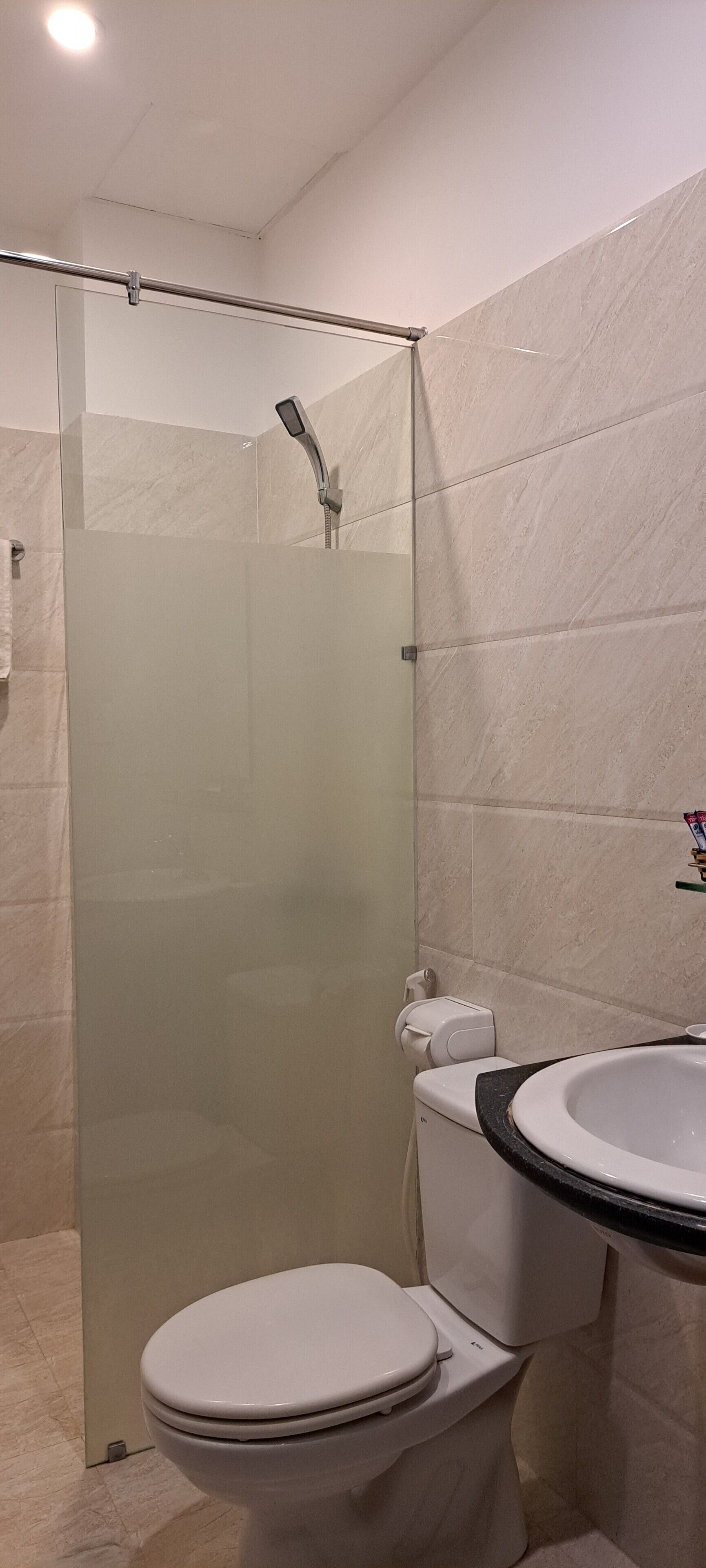A modern bathroom with a glass-enclosed shower, a white toilet, and a sink with a black countertop.