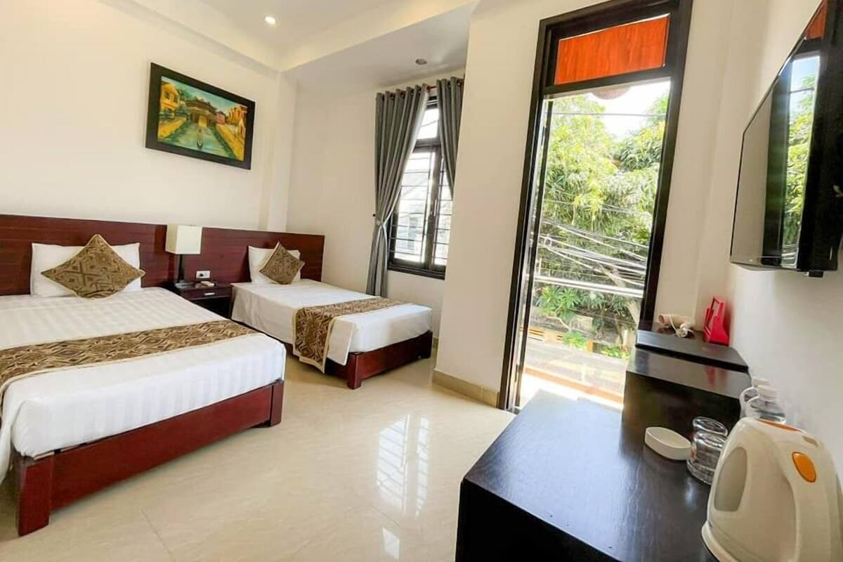A hotel room with two beds, a TV, a coffee maker, and a balcony with a view.