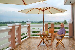 Relax on the balcony with a view of the river and lush greenery, where you can unwind with a refreshing drink.