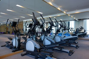 A gym with multiple cardio machines, including treadmills and elliptical trainers, arranged in rows. - Grand Royal Hotel (Toufen)