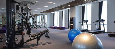 A gym with exercise equipment, treadmills, and exercise balls.