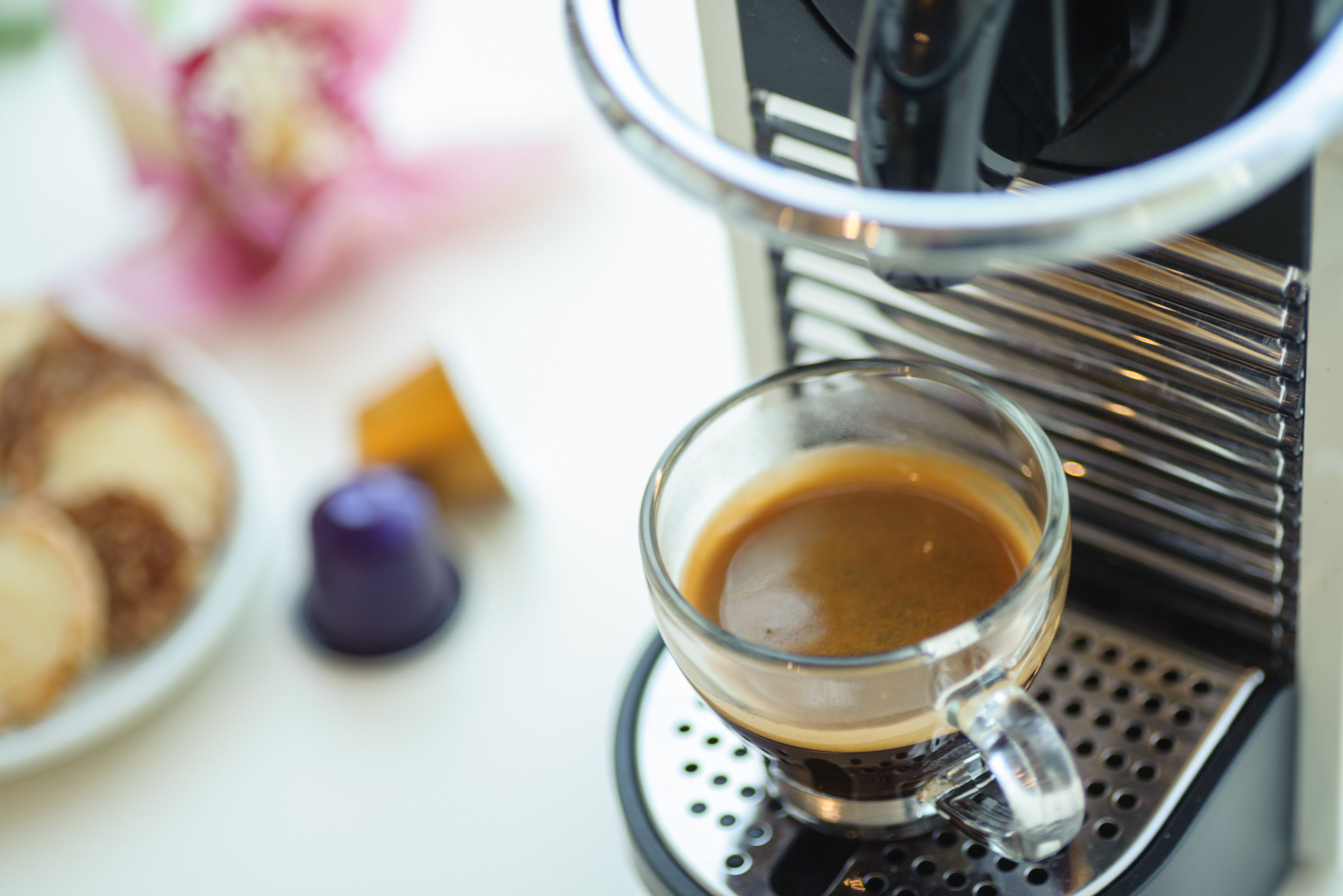 A coffee machine dispensing coffee into a glass cup.