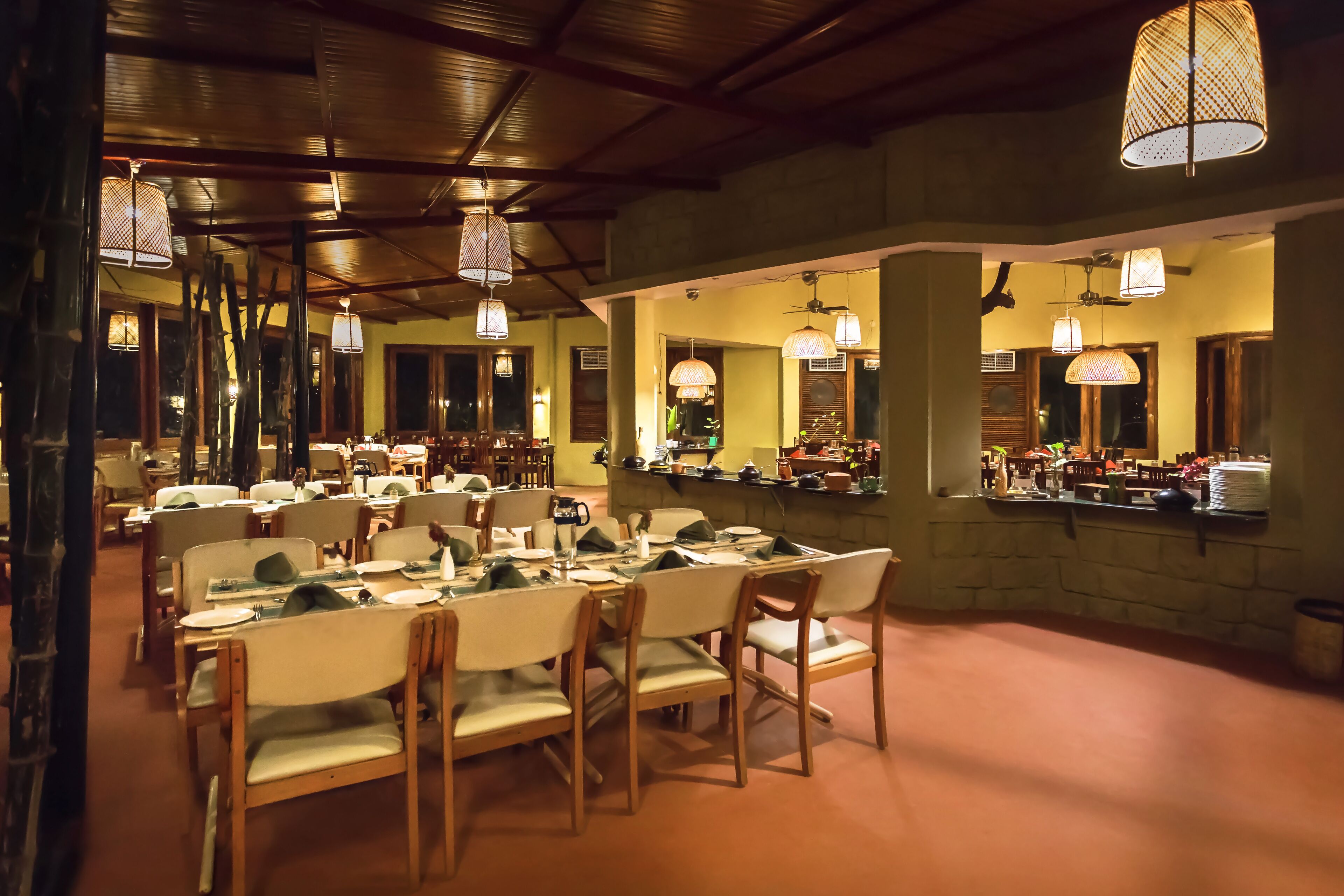 Een restaurant met houten tafels en stoelen, hanglampen en een stenen muur.