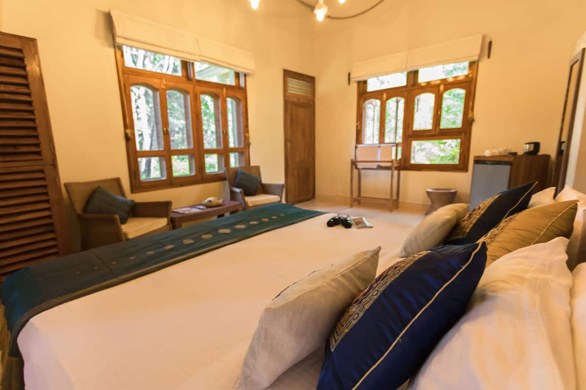 A bedroom with a large bed, two windows, a desk, and a chair.