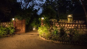 Une entrée fermée par un portail mène à un terrain de camping où un panneau indique : « Pench Jung Camp ».