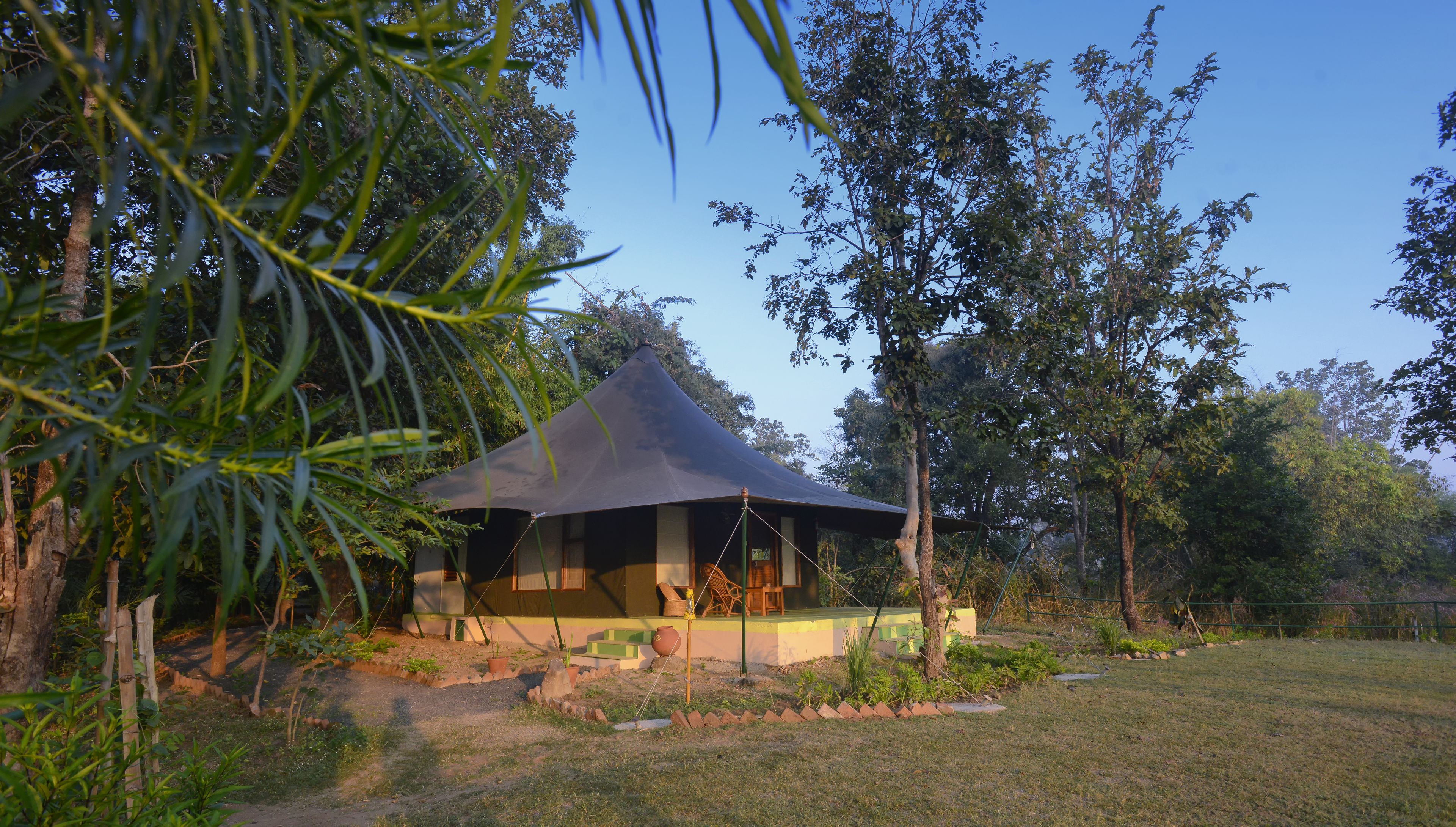 Een paviljoen met een kegelvormig dak, omringd door een tuin met diverse planten en bomen.