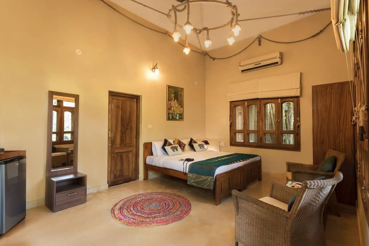 A bedroom with a bed, a chair, a desk, and a mirror.