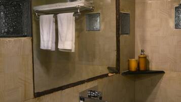 Une salle de bain avec un grand miroir, un lavabo blanc et un vase rempli de fleurs jaunes.