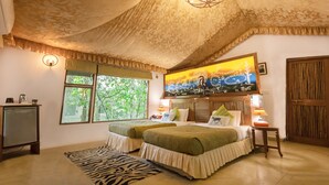 Une chambre avec deux lits, un tapis à motifs zébrés, un plafond orné de motifs floraux, un tableau au-dessus du lit et une porte en bois.