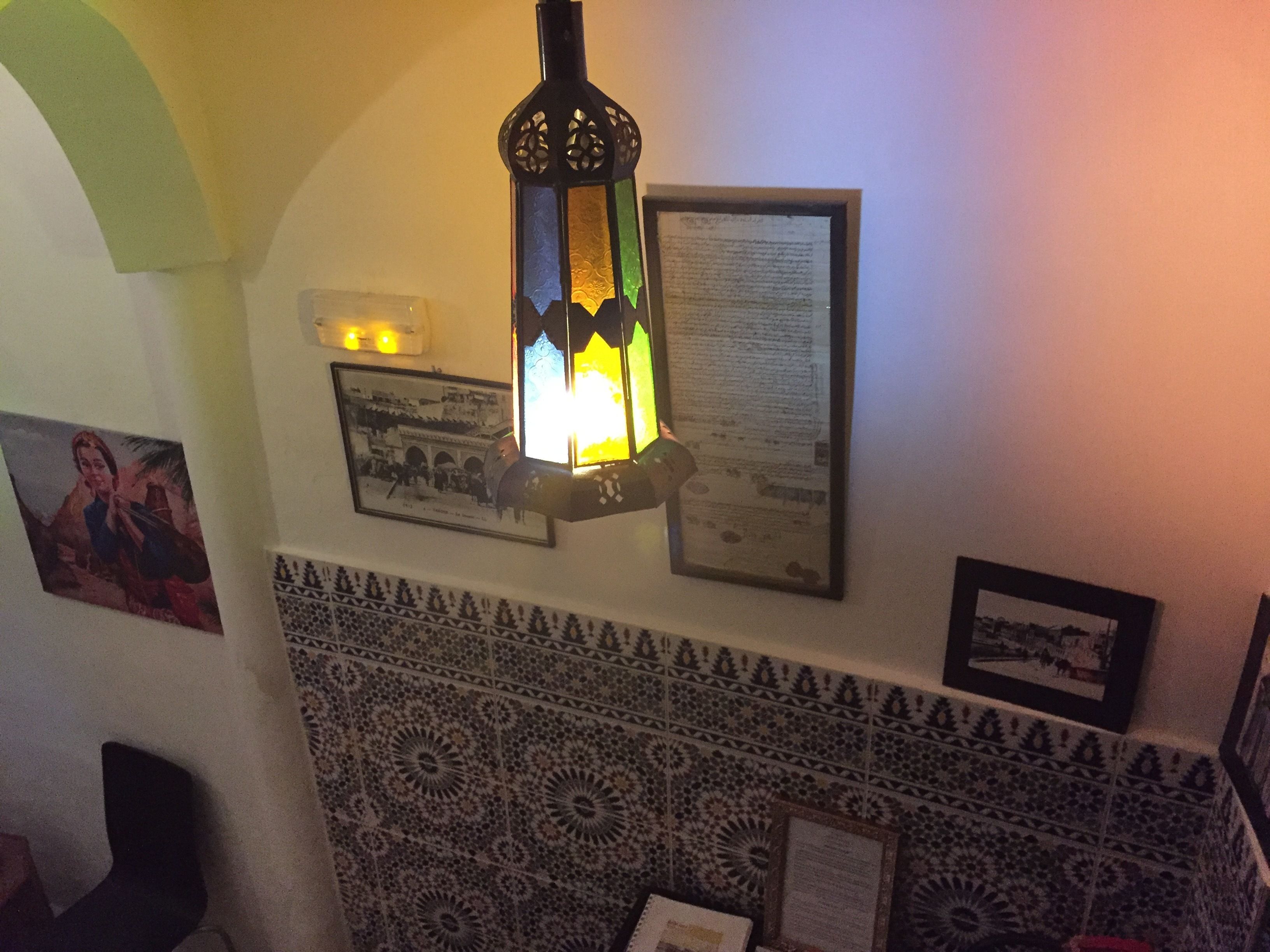Una pared con un farol decorativo, fotografías enmarcadas y un rebozo de azulejos.
