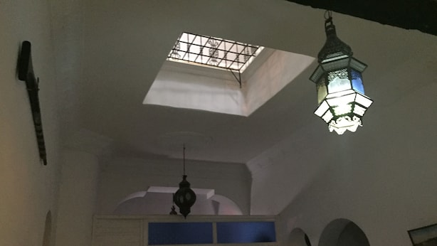 Una habitación con tragaluz, un farol colgante y un acceso a otra estancia.