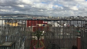 Un balcón con vistas a un paisaje urbano costero, que incluye edificios y una masa de agua.