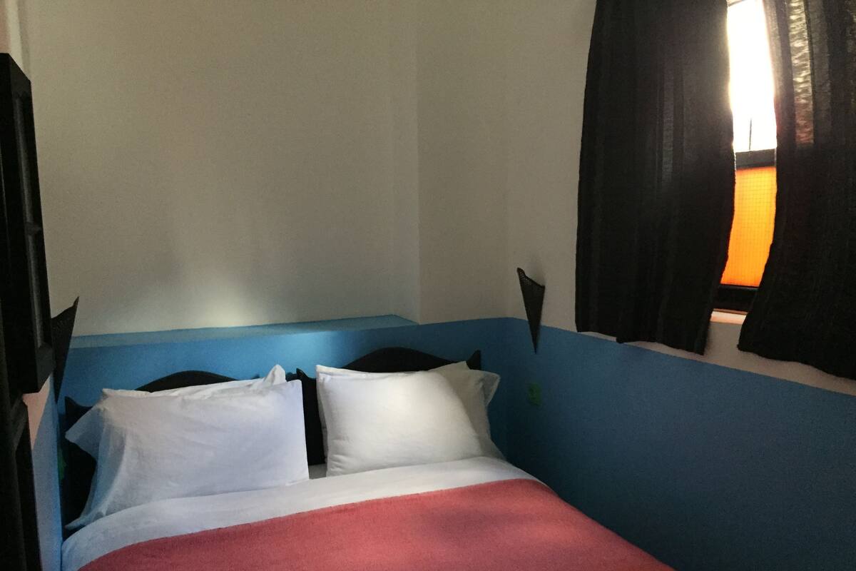 A bed with a red blanket, white pillows, and a blue headboard.