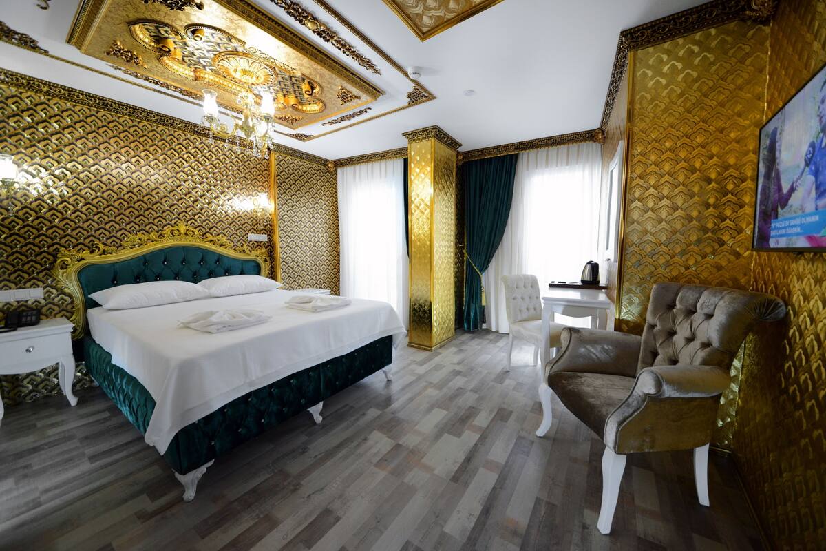 Una lujosa habitación de hotel con una cama grande, una zona de estar con una silla y un escritorio.