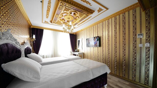 A luxurious hotel room with a large bed, ornate ceiling, and a television. - Babel Park Hotel (Istanbul)