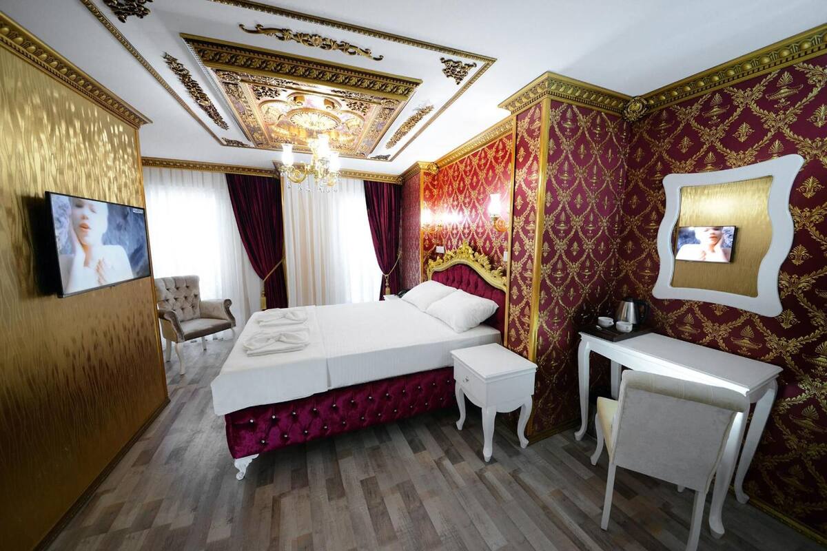 Un dormitorio lujoso con una cama grande, un tocador y un televisor montado en la pared.