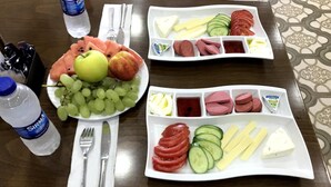 A table with plates of food including fruits, cheese, and meats, along with water bottles and cutlery. - Babel Park Hotel (Istanbul)
