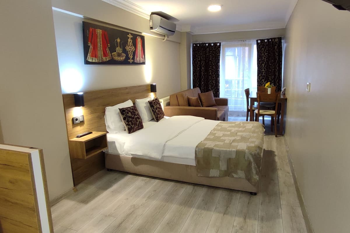 A hotel room with a bed, bedside table, lamp, and a painting on the wall.
