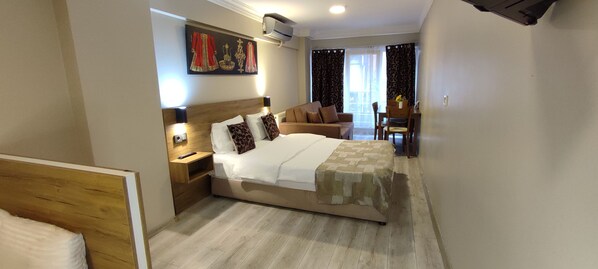 A hotel room with a bed, bedside table, lamp, and a painting on the wall.