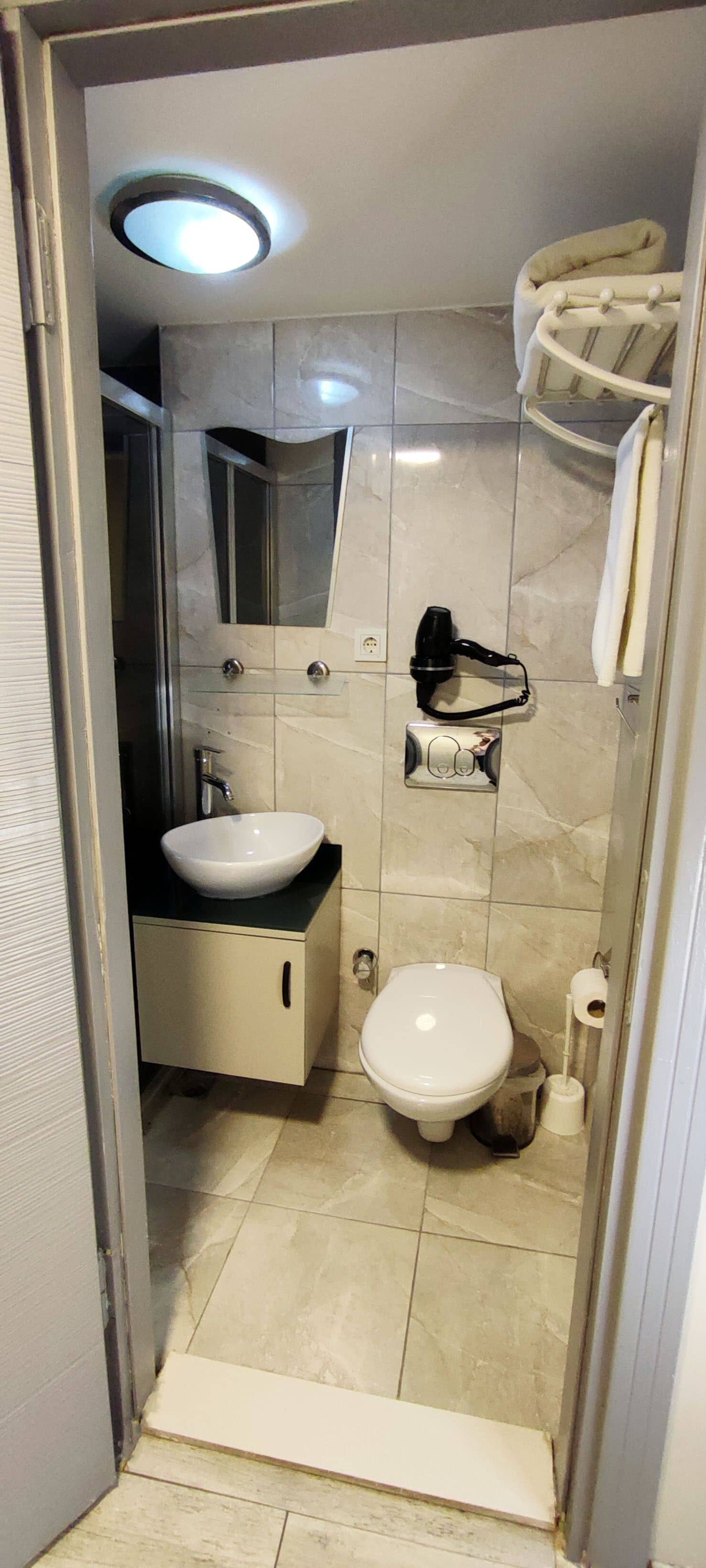 A compact bathroom with a sink, toilet, and a mirror.