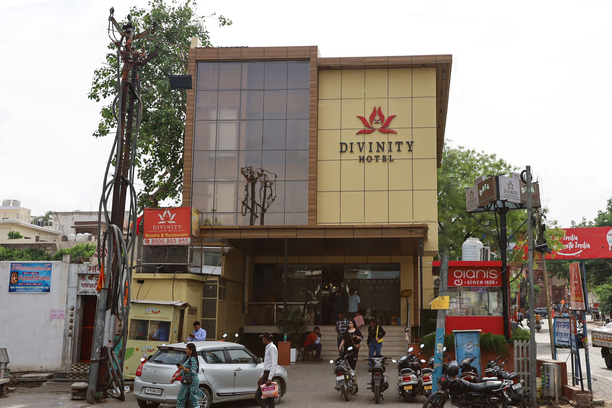 The exterior of the Divinity Hotel with a prominent entrance, a signboard, and a visible staircase leading to the entrance.