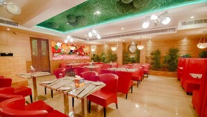 A restaurant with red chairs and tables, a green ceiling, and a clock on the wall. - Divinity By Audra Hotels (Mathura)