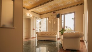 A hotel lobby with a marble floor, a sofa, and a large window with a view of palm trees. - Hotel Villa Maranello (Maranello)