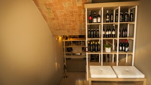 A wine cellar with shelves of wine bottles and a small potted plant. - Hotel Villa Maranello (Maranello)